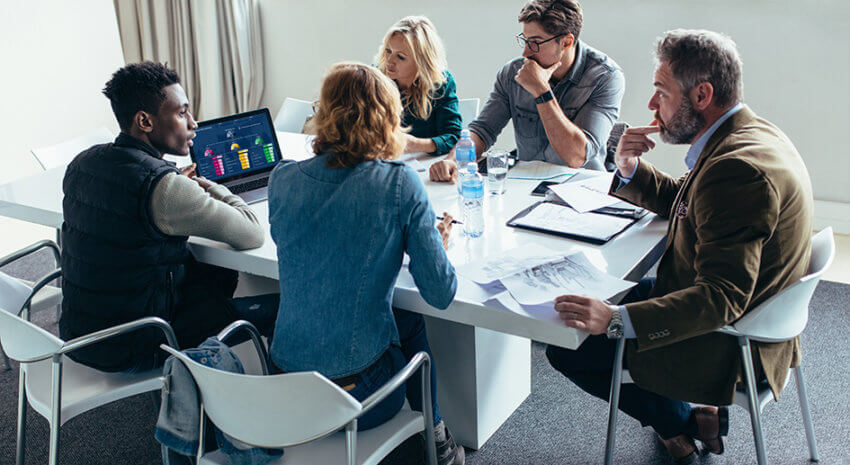 Team of five people working together around a meeting table