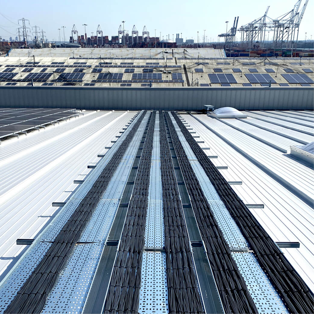 Dark solar panels and electrical cabling installed on a white building roof