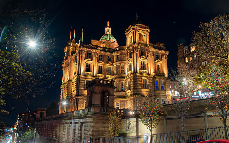 Side of building lit up with natural tone lights at night