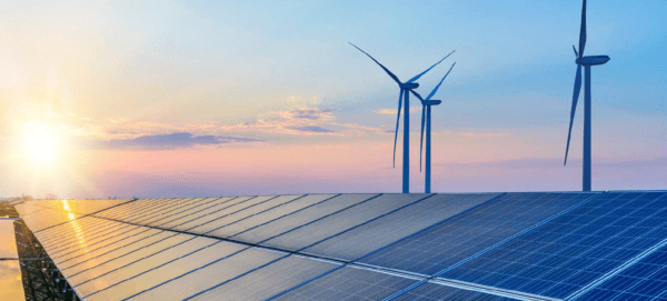 Wind turbines and solar panels against a setting sun