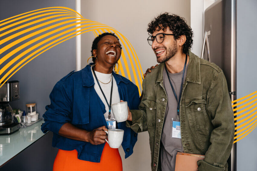 Office employees laughing together on a coffee break. Colleagues building friendship in a professional environment.