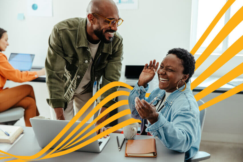 Employees enjoying each other's company, laughing, and bonding in a fun and collaborative office culture with laptops.